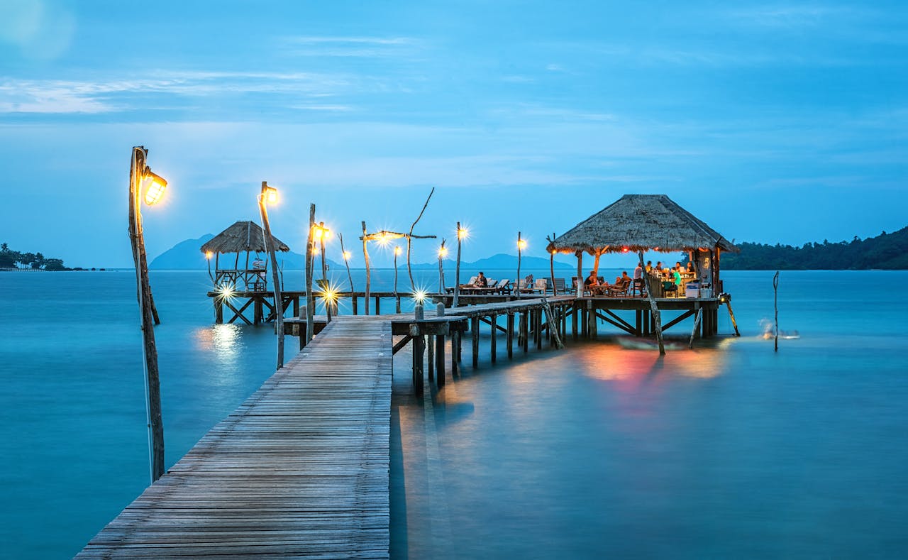 gallery-03 Illuminated pier and bungalow on a tranquil tropical sea at twilight.