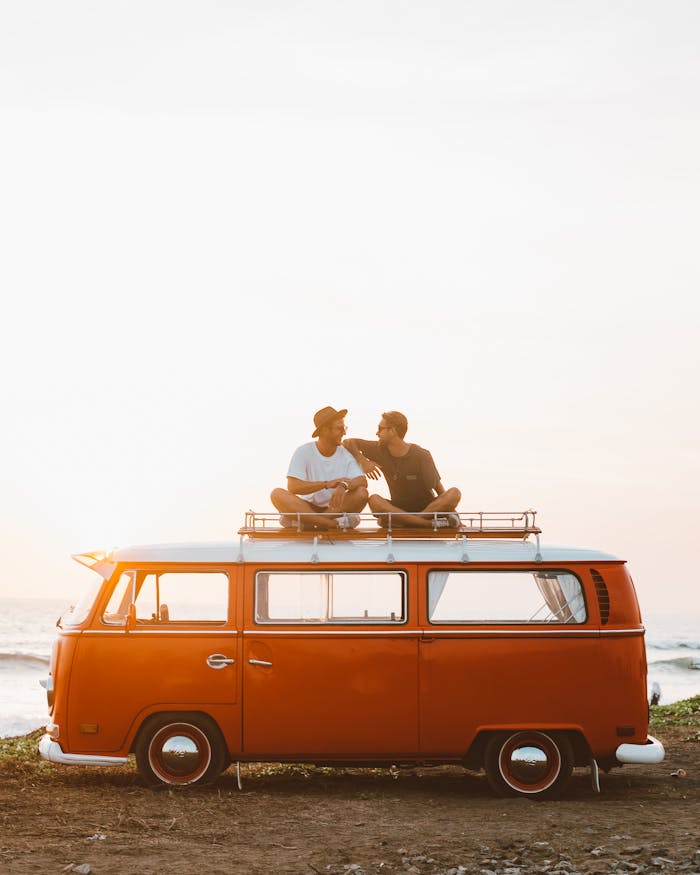 gallery-01 Silhouettes of full body faceless male friends in casual clothes resting on camper van roof and chatting in countryside in sunset time